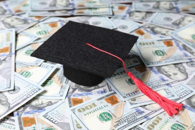 Photo of Graduate hat on dollar banknotes, closeup. Tuition payment