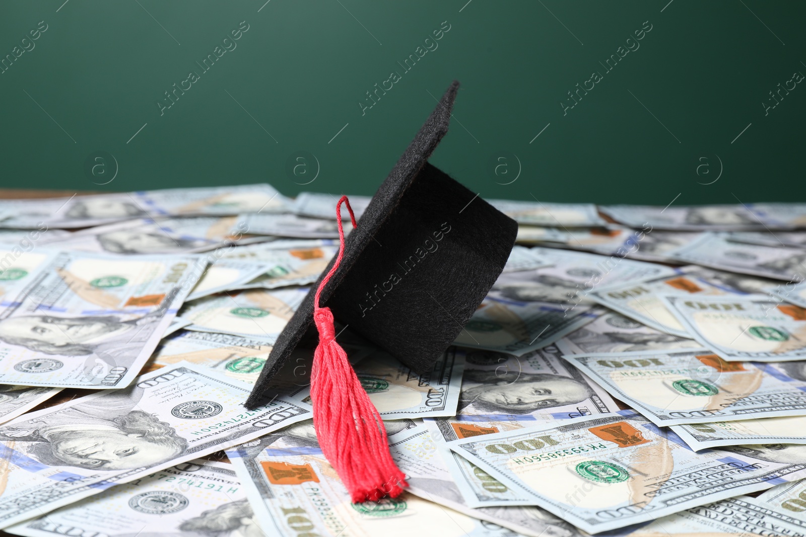 Photo of Graduate hat on dollar banknotes, closeup. Tuition payment