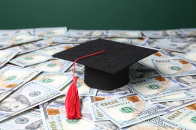 Photo of Graduate hat on dollar banknotes, closeup. Tuition payment