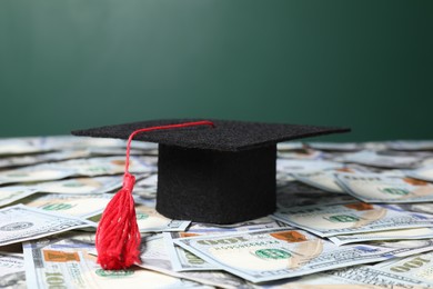 Photo of Graduate hat on dollar banknotes, closeup. Tuition payment