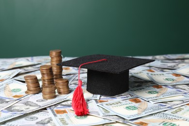 Photo of Graduate hat and coins on dollar banknotes, closeup. Tuition payment