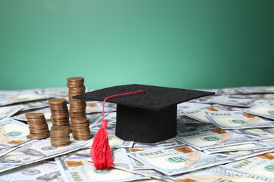 Photo of Graduate hat and coins on dollar banknotes, closeup. Tuition payment