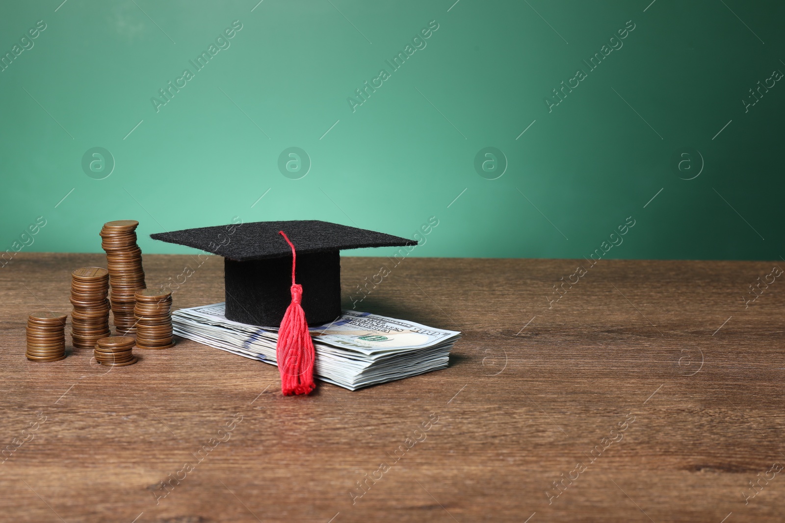 Photo of Graduate hat, dollar banknotes and coins on wooden table, space for text. Tuition payment