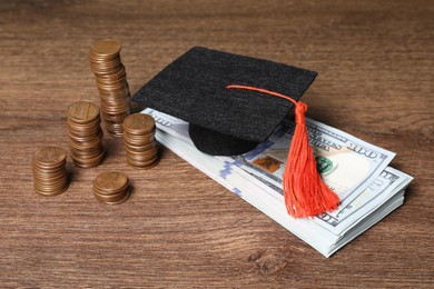 Photo of Graduate hat, dollar banknotes and coins on wooden table, closeup. Tuition payment