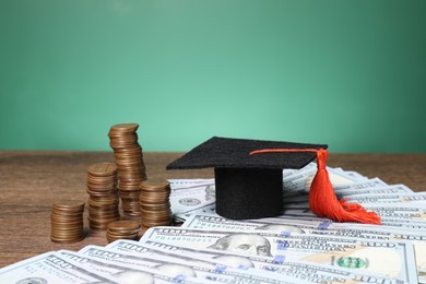 Photo of Graduate hat, dollar banknotes and coins on wooden table, closeup. Tuition payment