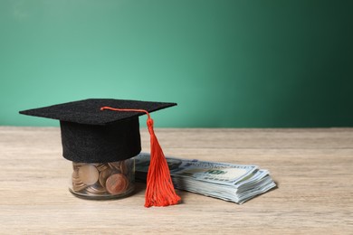 Photo of Graduate hat, dollar banknotes and coins on wooden table, closeup. Tuition payment