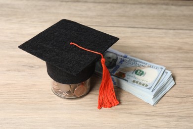 Photo of Graduate hat, dollar banknotes and coins on wooden table, closeup. Tuition payment