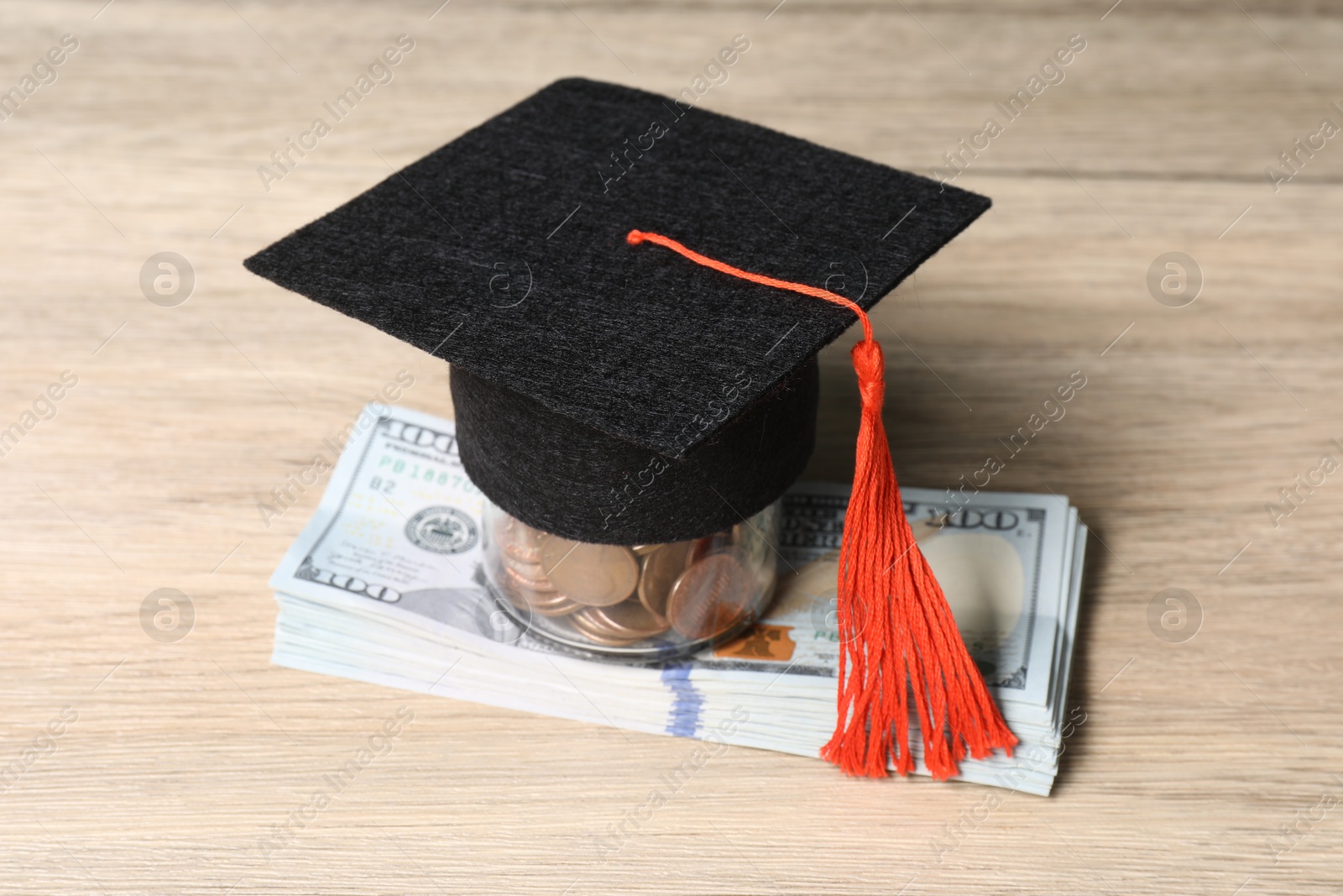 Photo of Graduate hat, dollar banknotes and coins on wooden table, closeup. Tuition payment