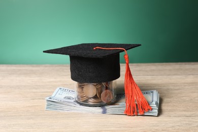 Photo of Graduate hat, dollar banknotes and coins on wooden table, closeup. Tuition payment