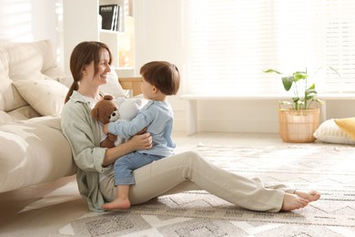 Photo of Happy mother and her cute little son with toy bear at home