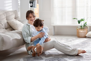 Photo of Happy mother and her cute little son with toy bear at home