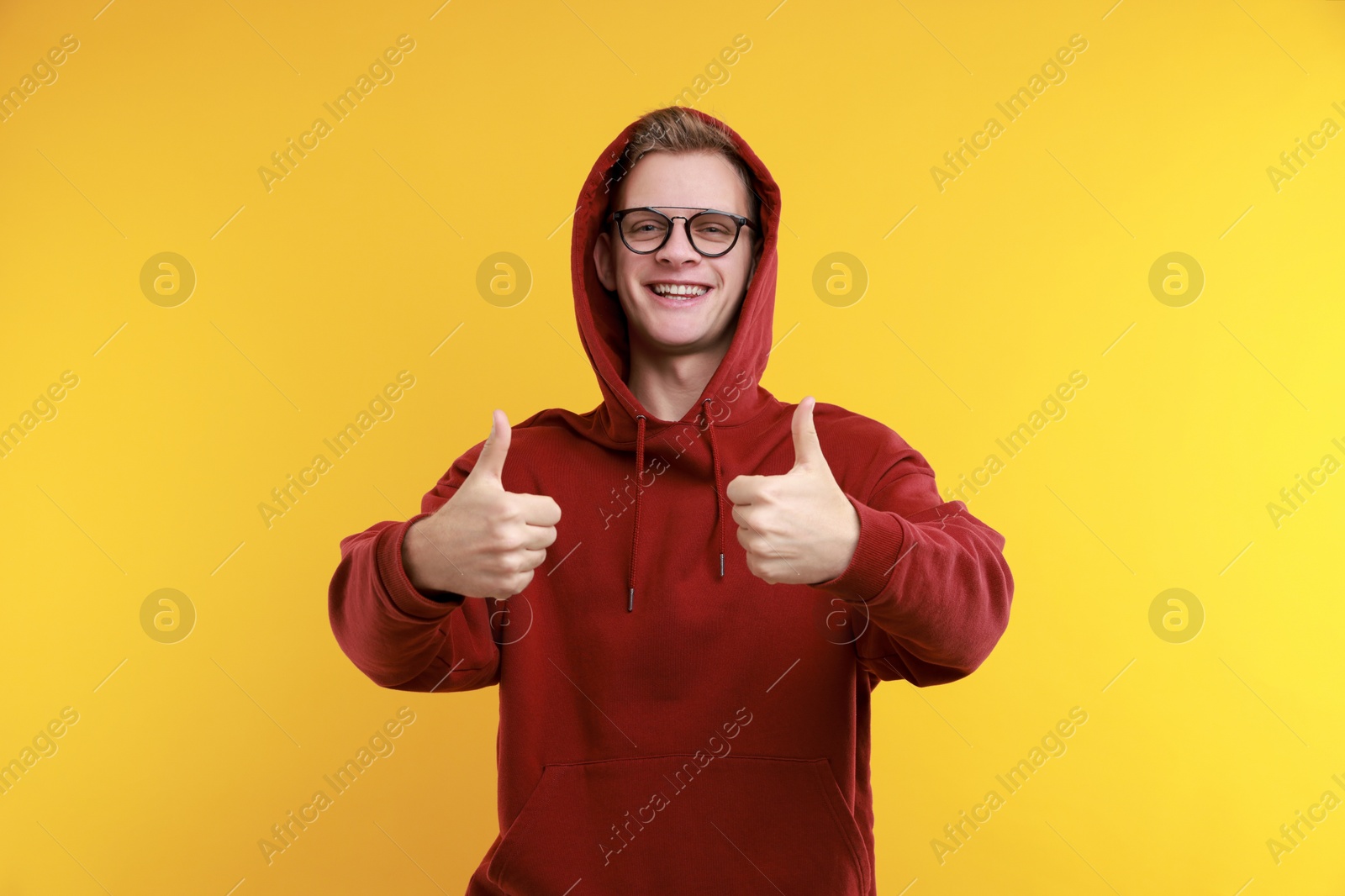 Photo of Happy man showing thumbs up on yellow background. Like gesture