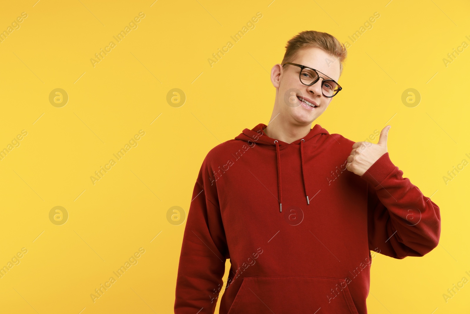 Photo of Happy man showing thumbs up on yellow background, space for text. Like gesture