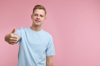 Photo of Happy man showing thumbs up on pink background, space for text. Like gesture