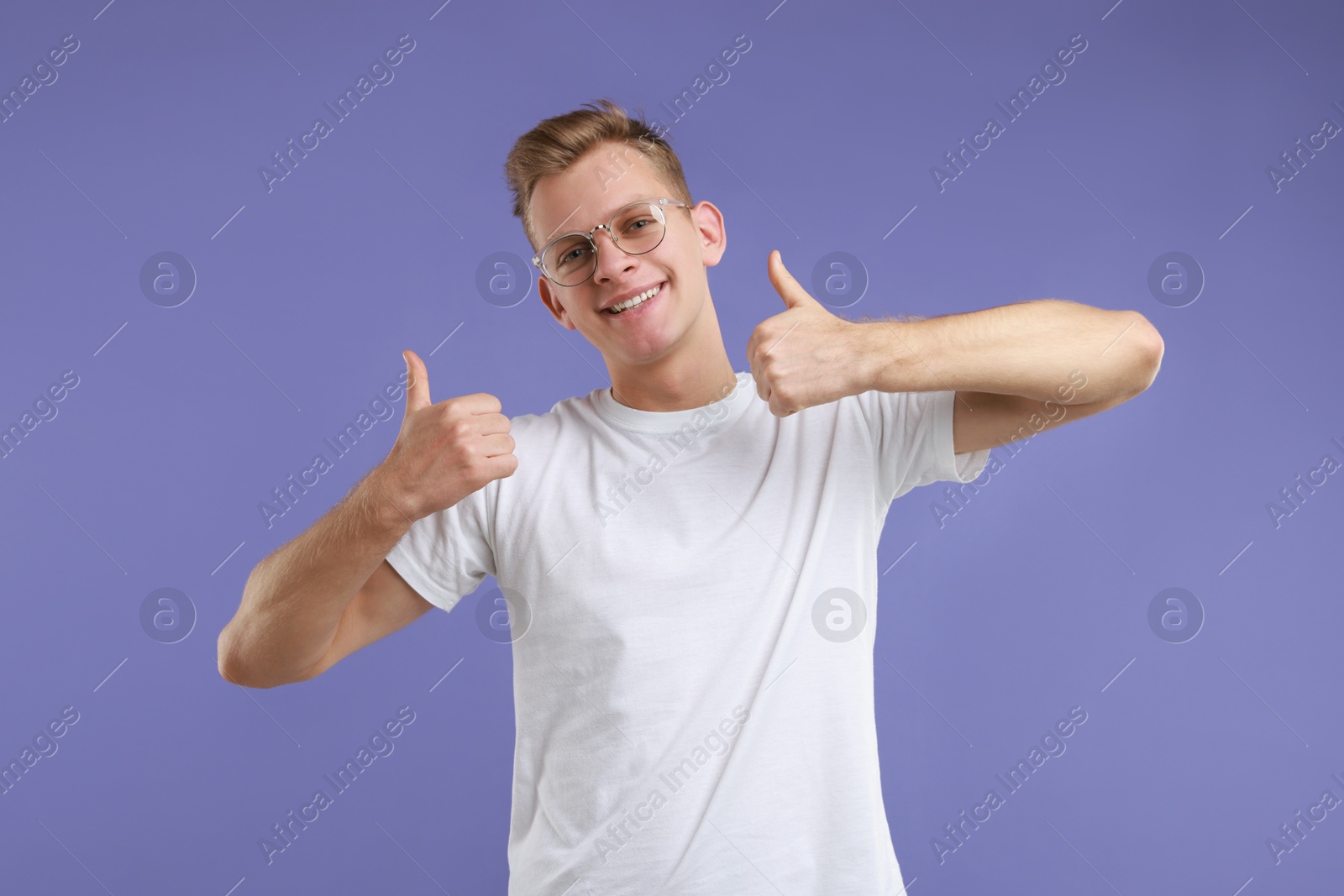 Photo of Happy man showing thumbs up on purple background. Like gesture