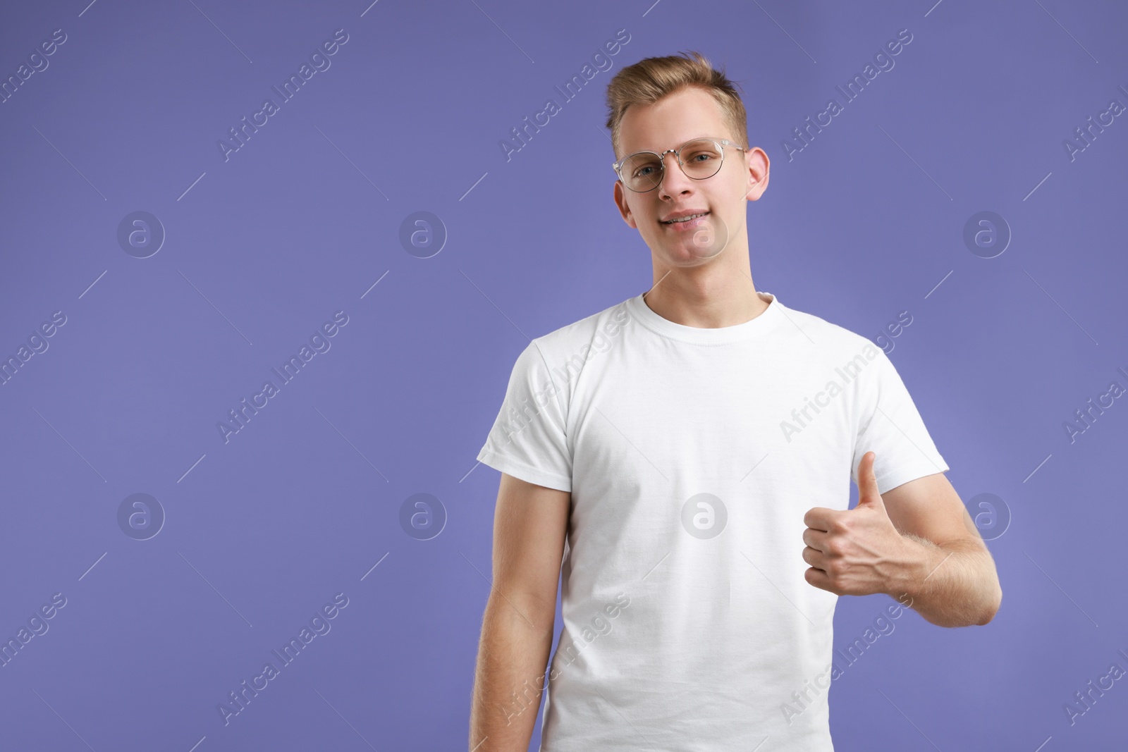 Photo of Happy man showing thumbs up on purple background, space for text. Like gesture