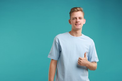 Happy man showing thumbs up on light blue background, space for text. Like gesture