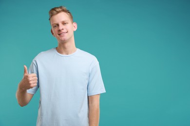 Photo of Happy man showing thumbs up on light blue background, space for text. Like gesture