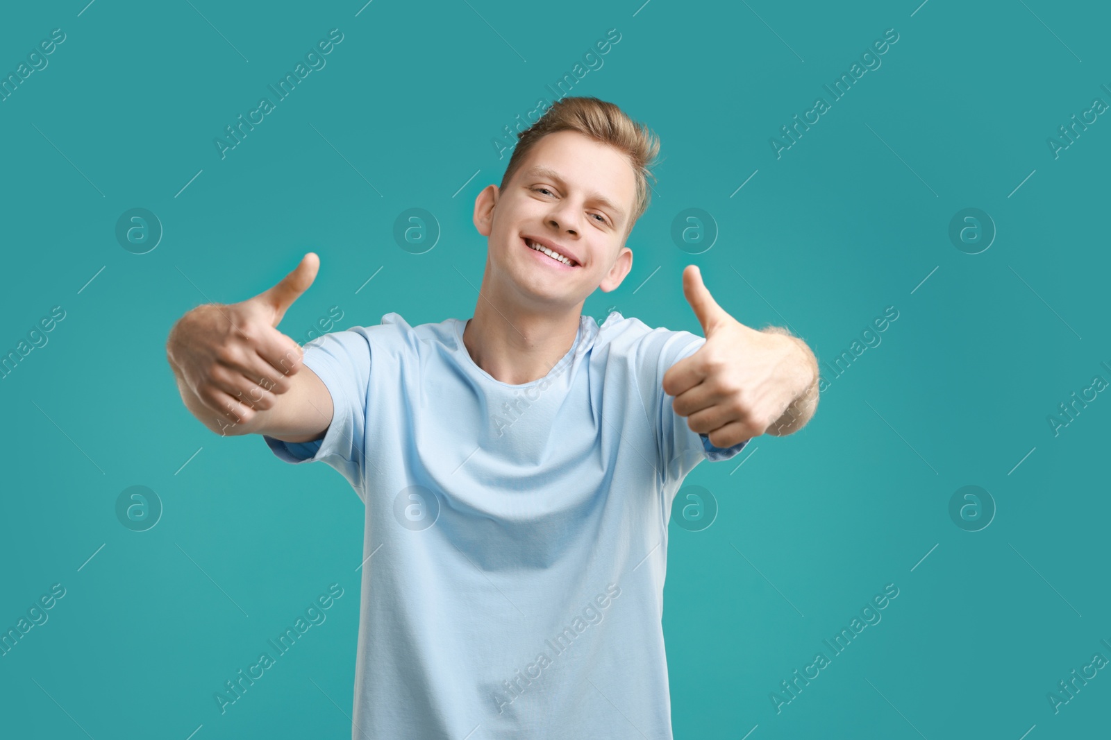 Photo of Happy man showing thumbs up on light blue background. Like gesture