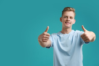 Photo of Happy man showing thumbs up on light blue background, space for text. Like gesture