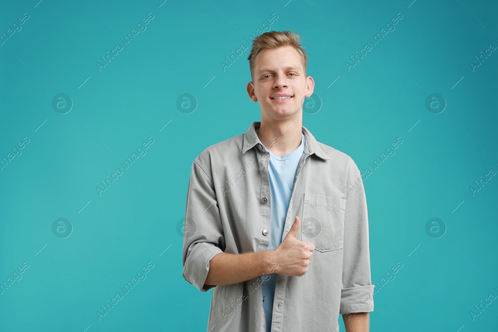 Photo of Happy man showing thumbs up on light blue background. Like gesture