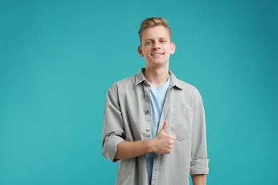 Happy man showing thumbs up on light blue background. Like gesture