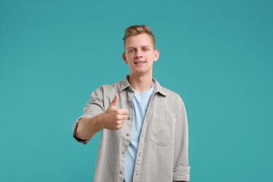 Photo of Happy man showing thumbs up on light blue background. Like gesture