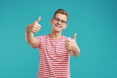 Photo of Happy man showing thumbs up on light blue background. Like gesture