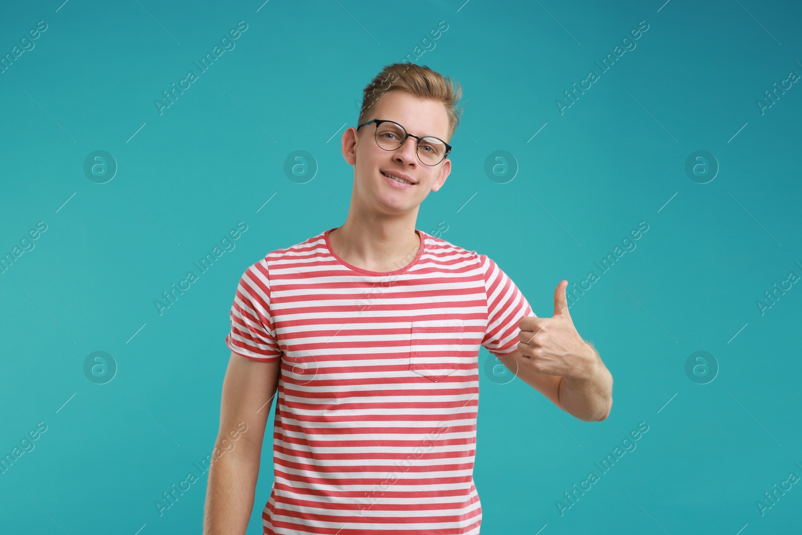 Photo of Happy man showing thumbs up on light blue background. Like gesture