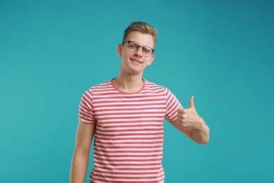 Photo of Happy man showing thumbs up on light blue background. Like gesture