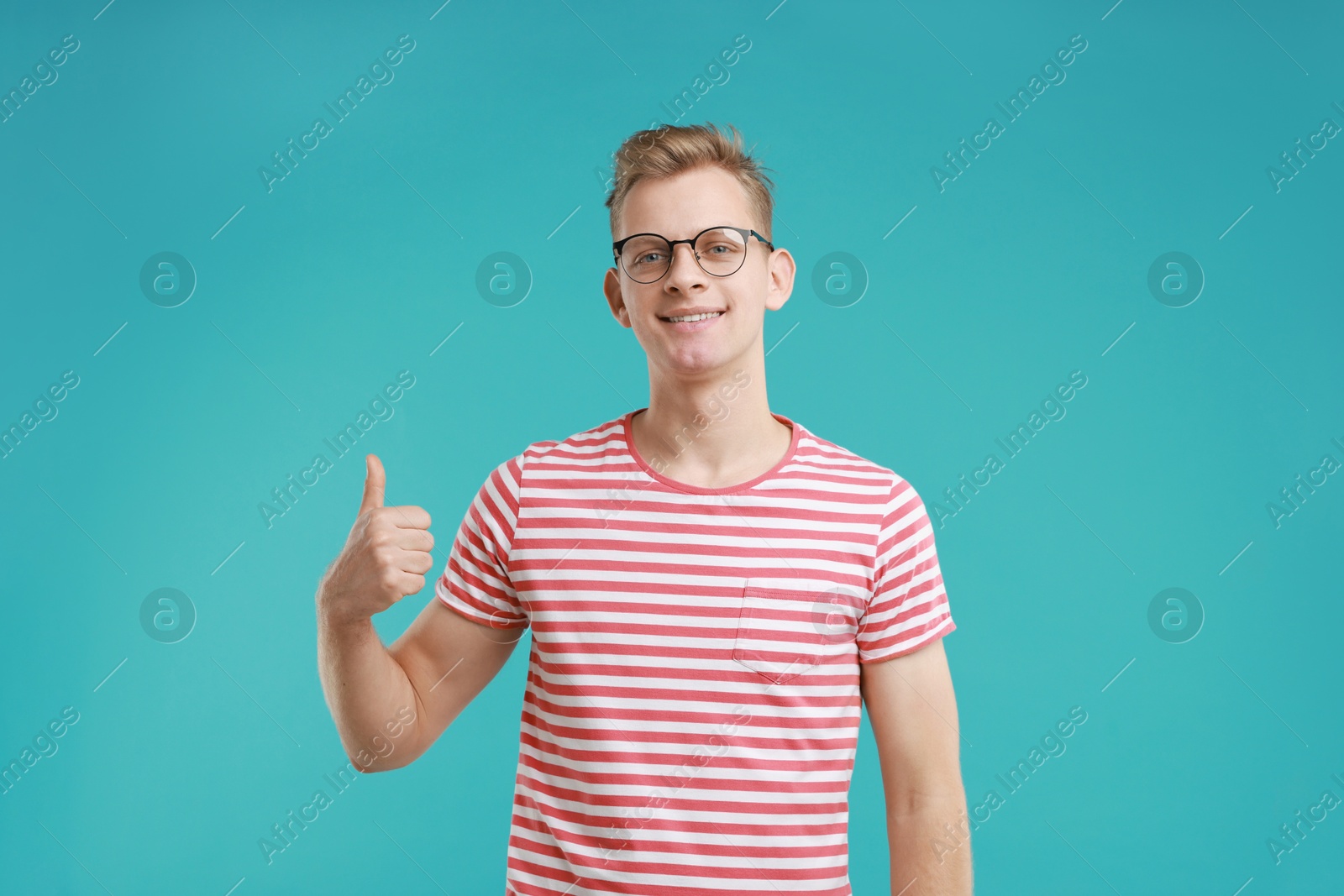 Photo of Happy man showing thumbs up on light blue background. Like gesture