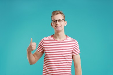 Happy man showing thumbs up on light blue background. Like gesture