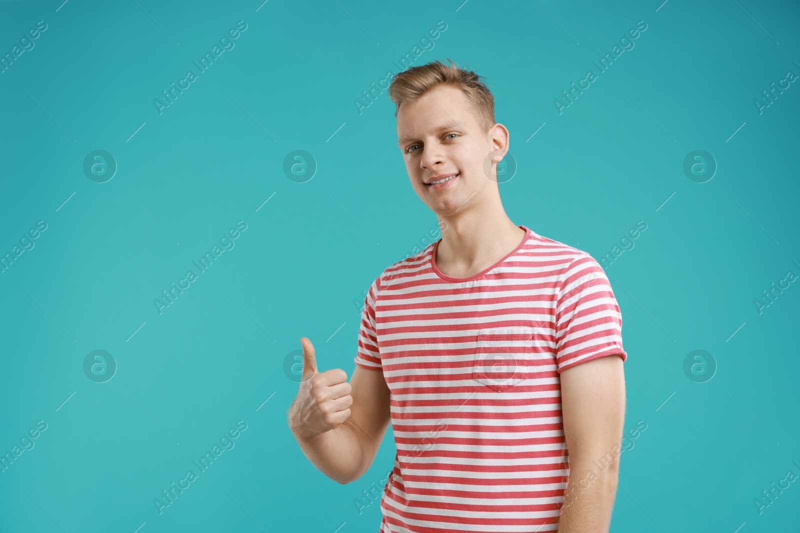 Photo of Happy man showing thumbs up on light blue background, space for text. Like gesture