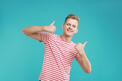 Photo of Happy man showing thumbs up on light blue background. Like gesture