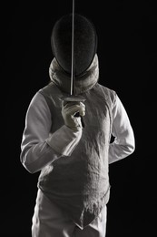 Photo of Fencer with epee on black background. Combat sport