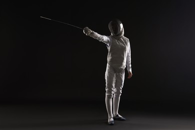 Photo of Fencer with epee practicing on dark background