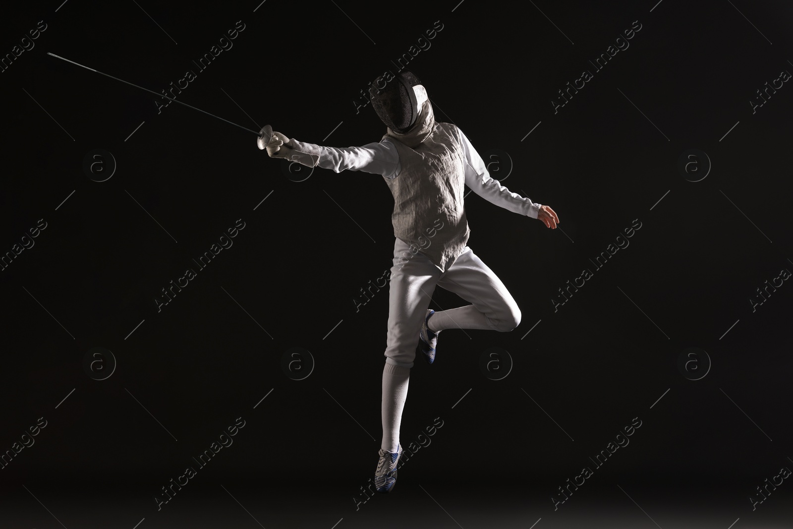 Photo of Fencer with epee practicing on black background