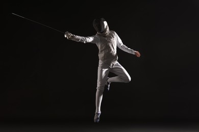 Photo of Fencer with epee practicing on black background