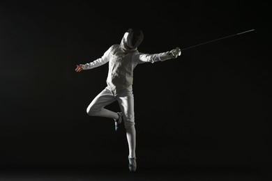 Photo of Fencer with epee practicing on black background