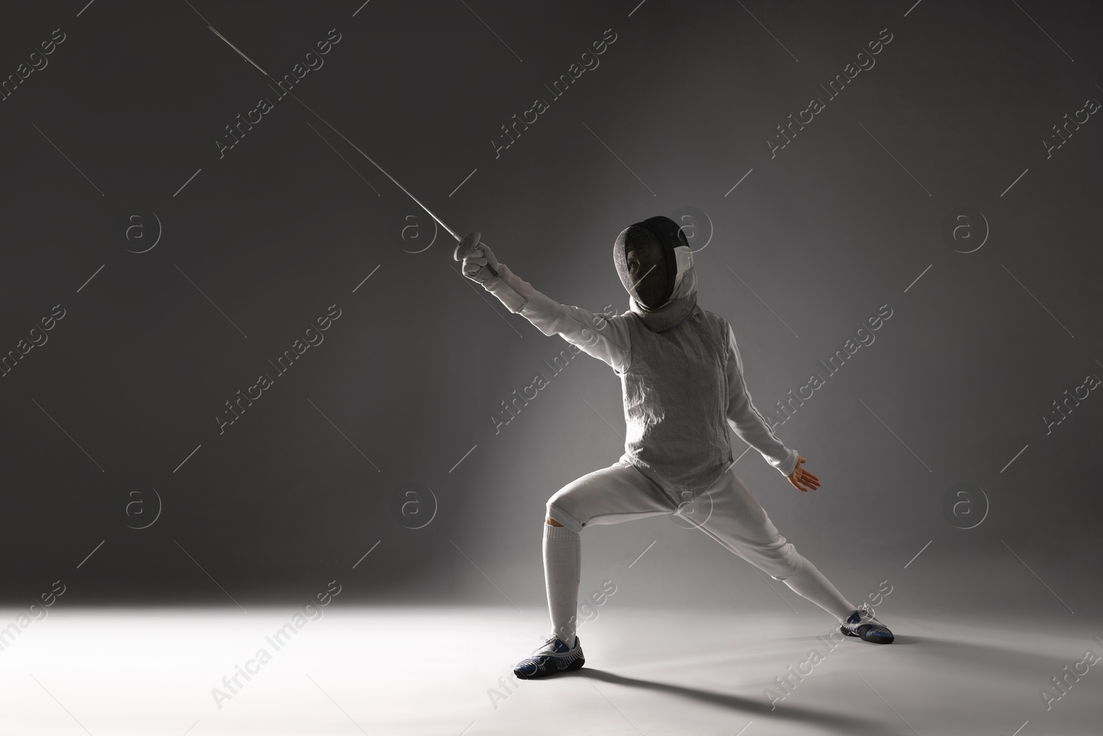 Photo of Fencer with epee practicing on gray background