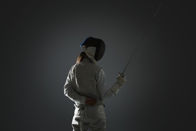 Photo of Fencer with epee on gray background. Combat sport