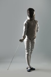 Photo of Fencer with epee on gray background. Combat sport