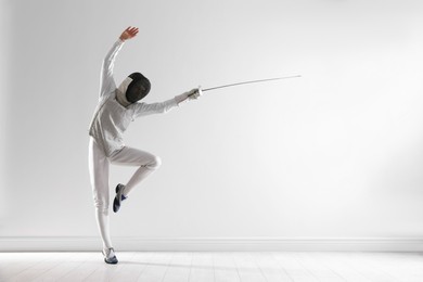 Photo of Fencer with epee practicing indoors, space for text