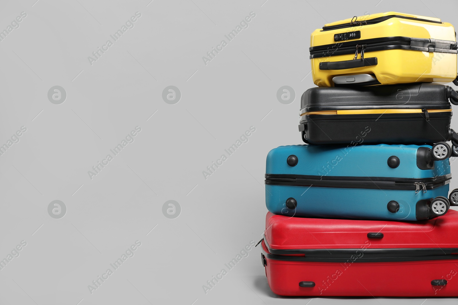 Photo of Stack of colorful suitcases on grey background. Space for text