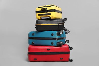 Photo of Stack of colorful suitcases on grey background