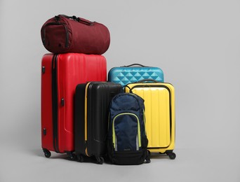 Photo of Many colorful suitcases, backpack and bag on grey background