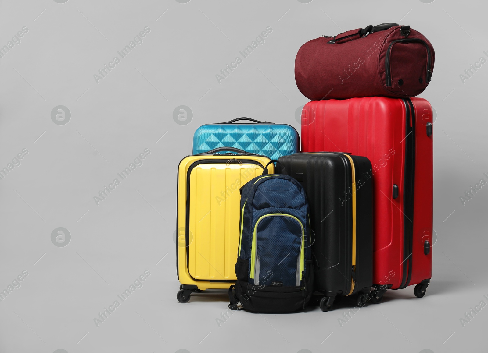 Photo of Many colorful suitcases, backpack and bag on grey background. Space for text