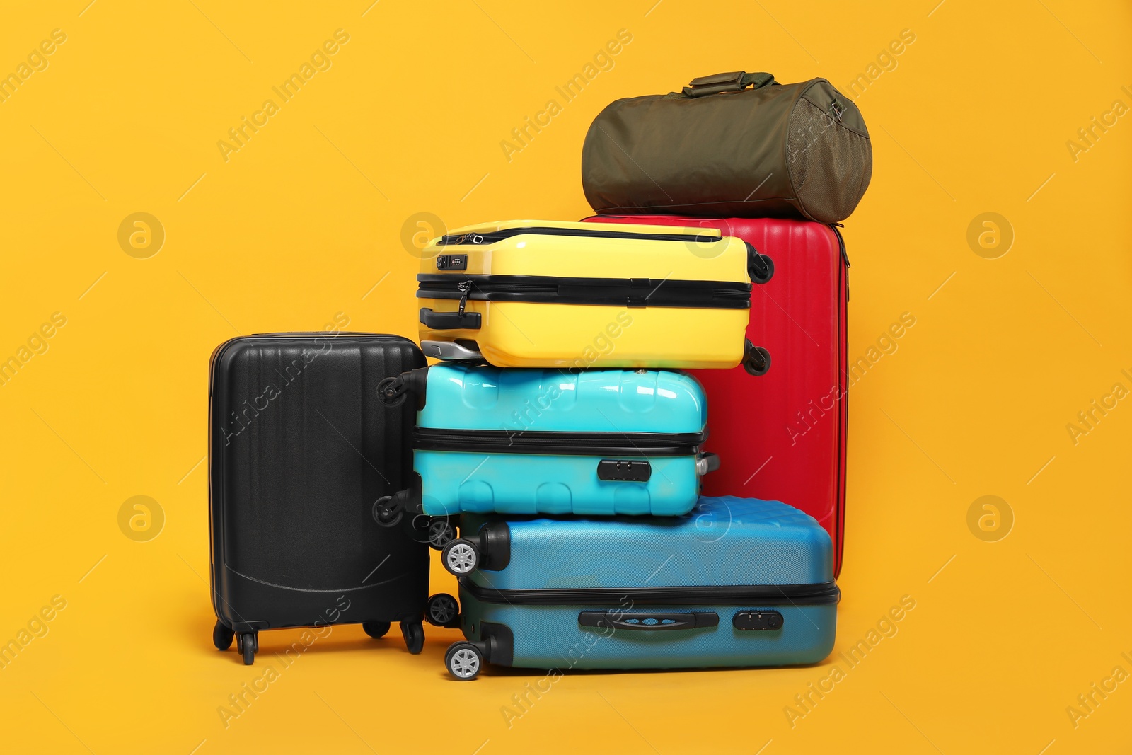 Photo of Many colorful suitcases and bag on orange background