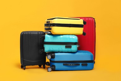 Photo of Many closed colorful suitcases on orange background