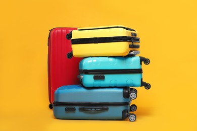 Photo of Many closed colorful suitcases on orange background